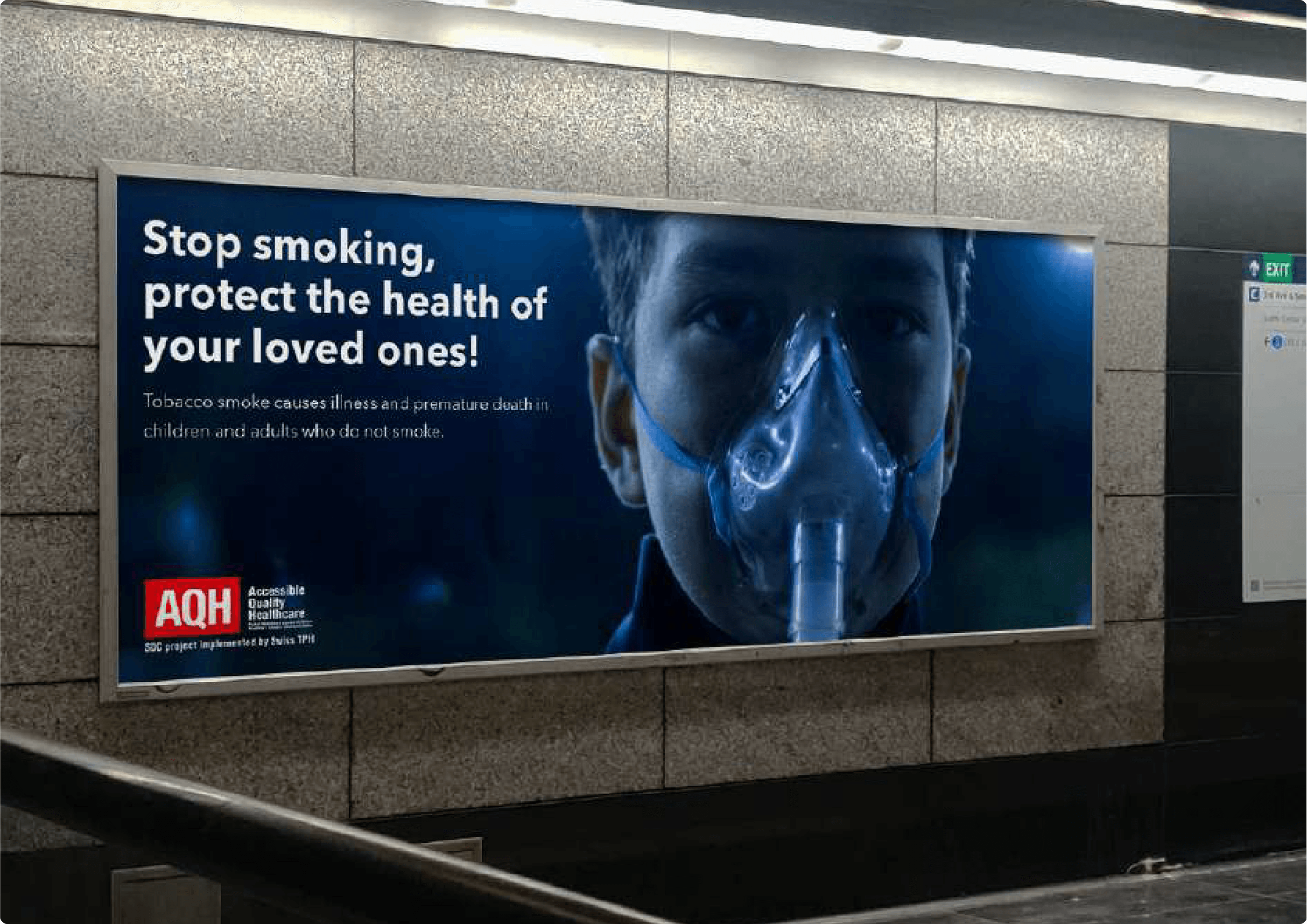 A large underground station billboard for AQH showing a young boy wearing an oxygen mask, with the headline 'Stop smoking, protect the health of your loved ones.'
