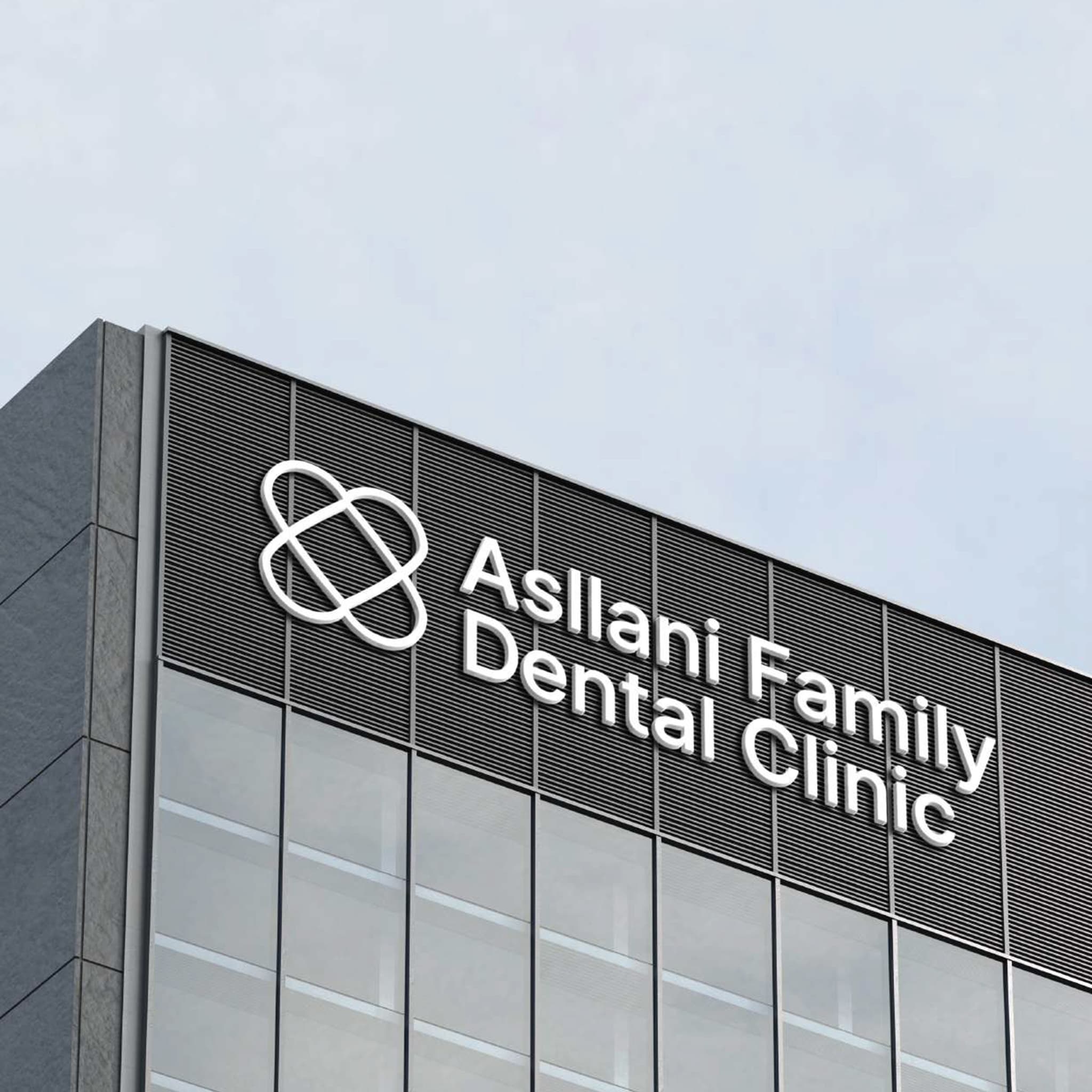 The Asllani Family Dental Clinic logo rendered as white architectural signage on the dark fascia of a modern building, with glass facade below.