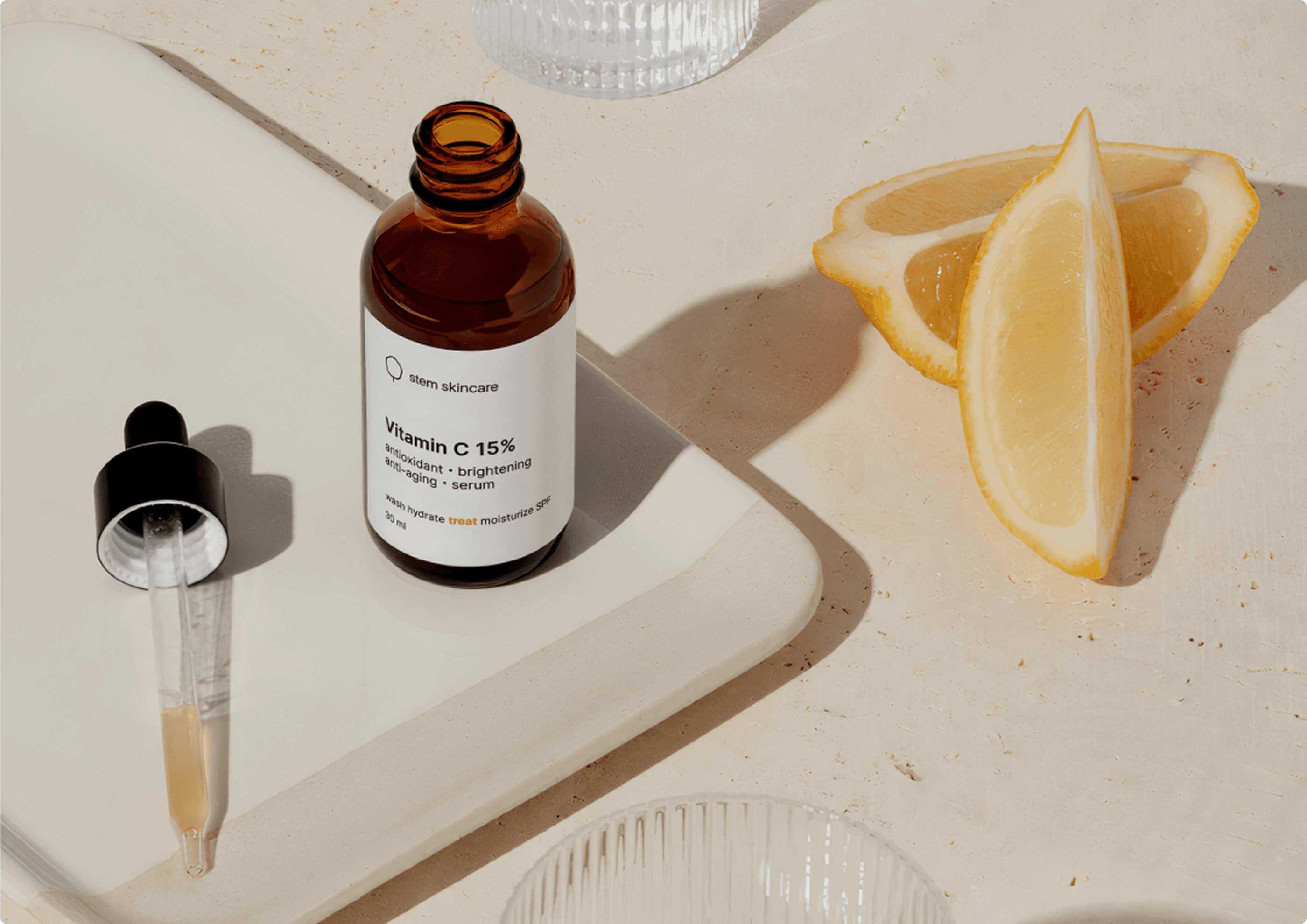 Editorial flatlay of the Stem Skincare Vitamin C serum bottle on a stone tray with sliced lemon and dropper.