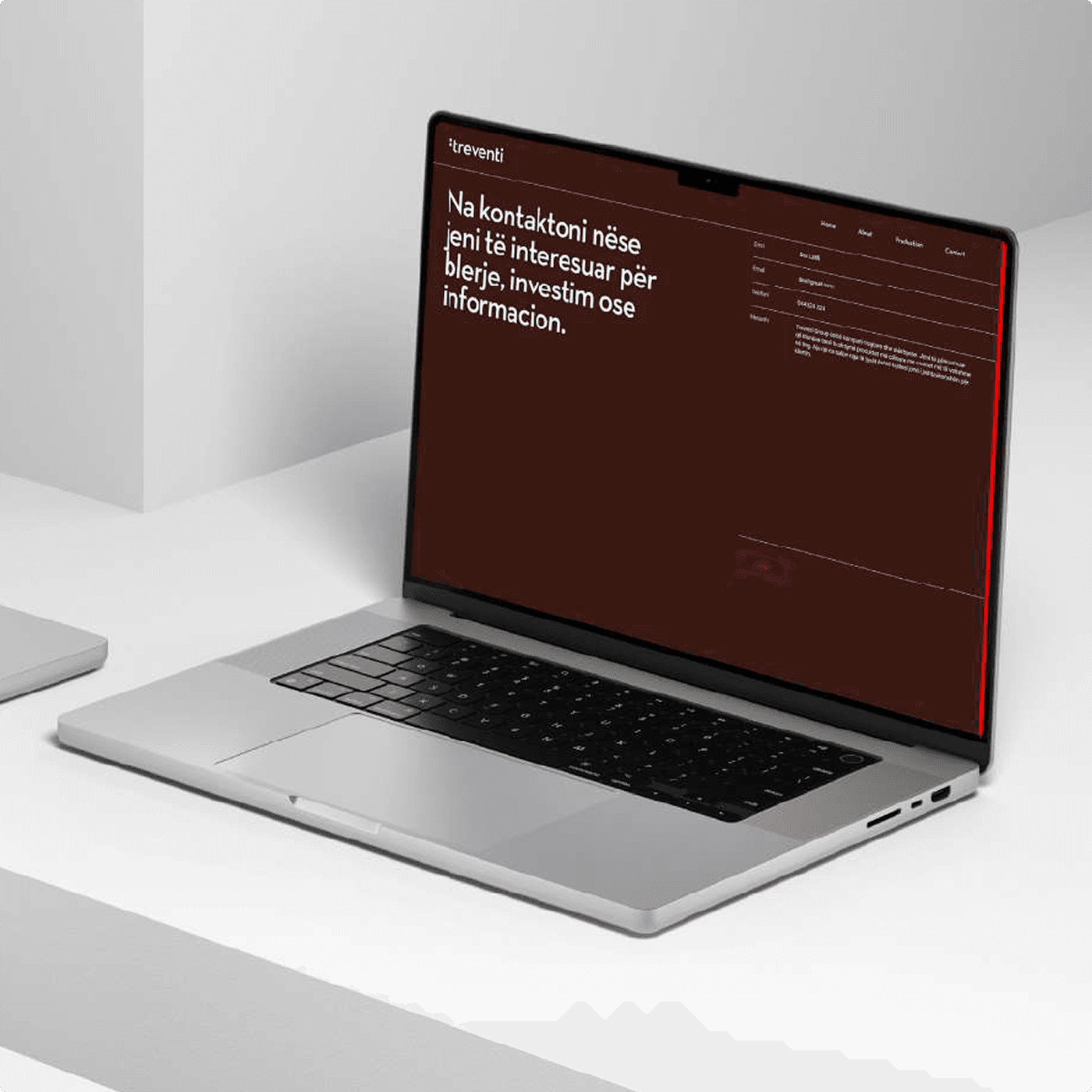 Ein Laptop auf einem hellen Tisch zeigt den Kontaktbereich der Treventi-Website — albanische Texte auf dem markentypischen Rot.